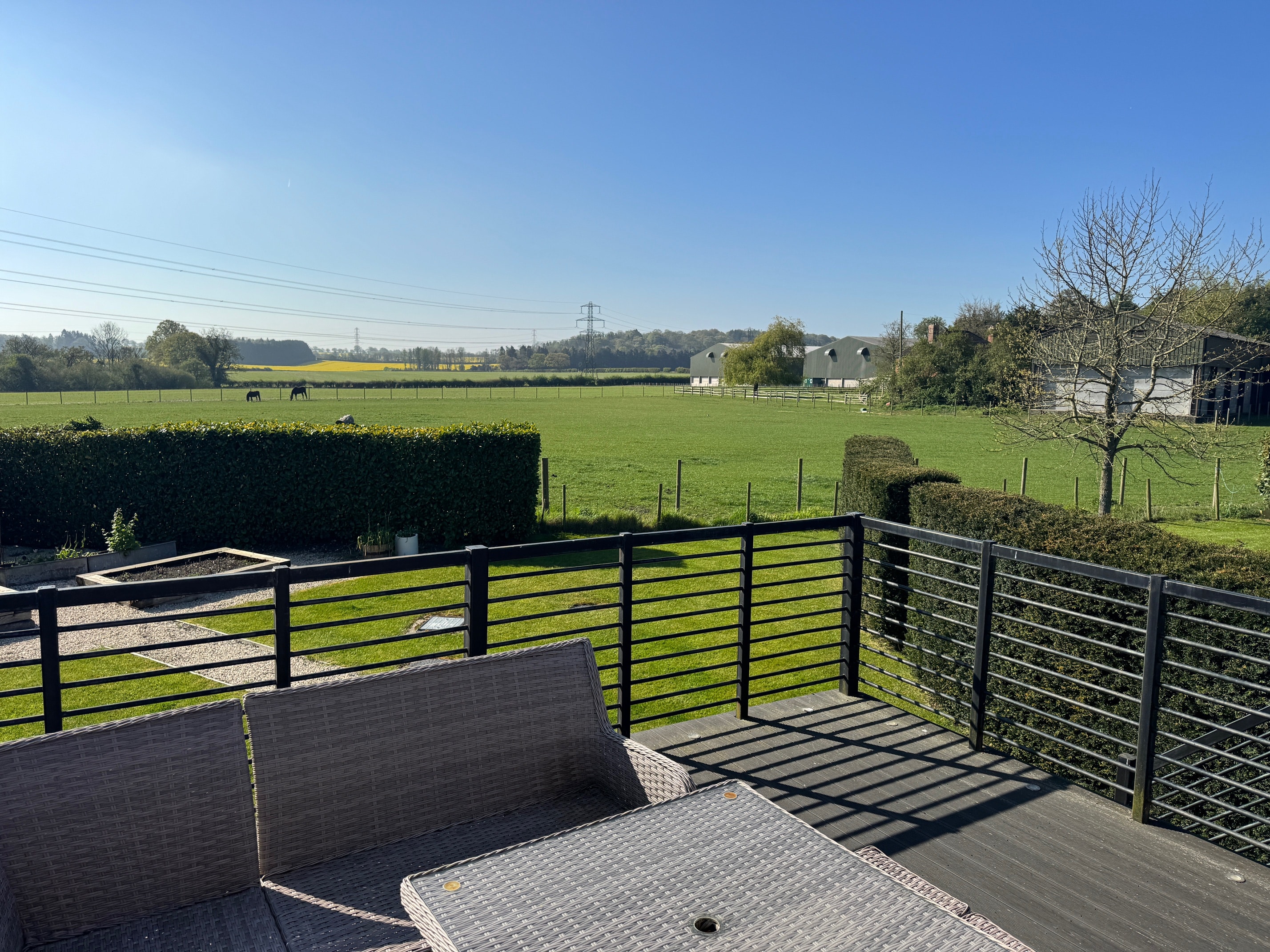 View from the balcony across green fields with horses and farm buildings