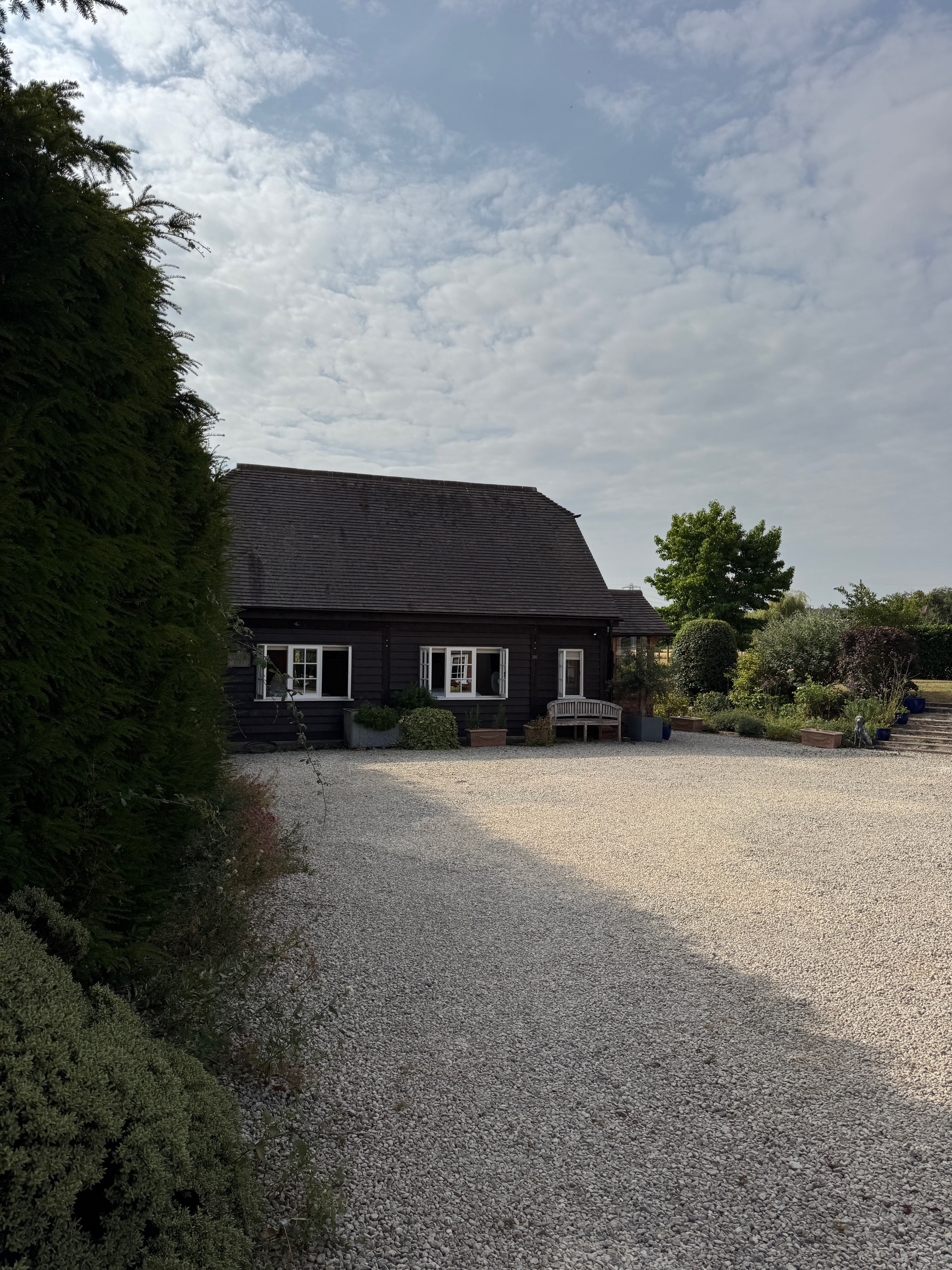 Neatham Barn timber exterior beside its gravel courtyard and garden